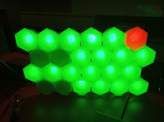 A bunch of hexagons in 4 rows, 6 each with all green and one in the upper right corner red.